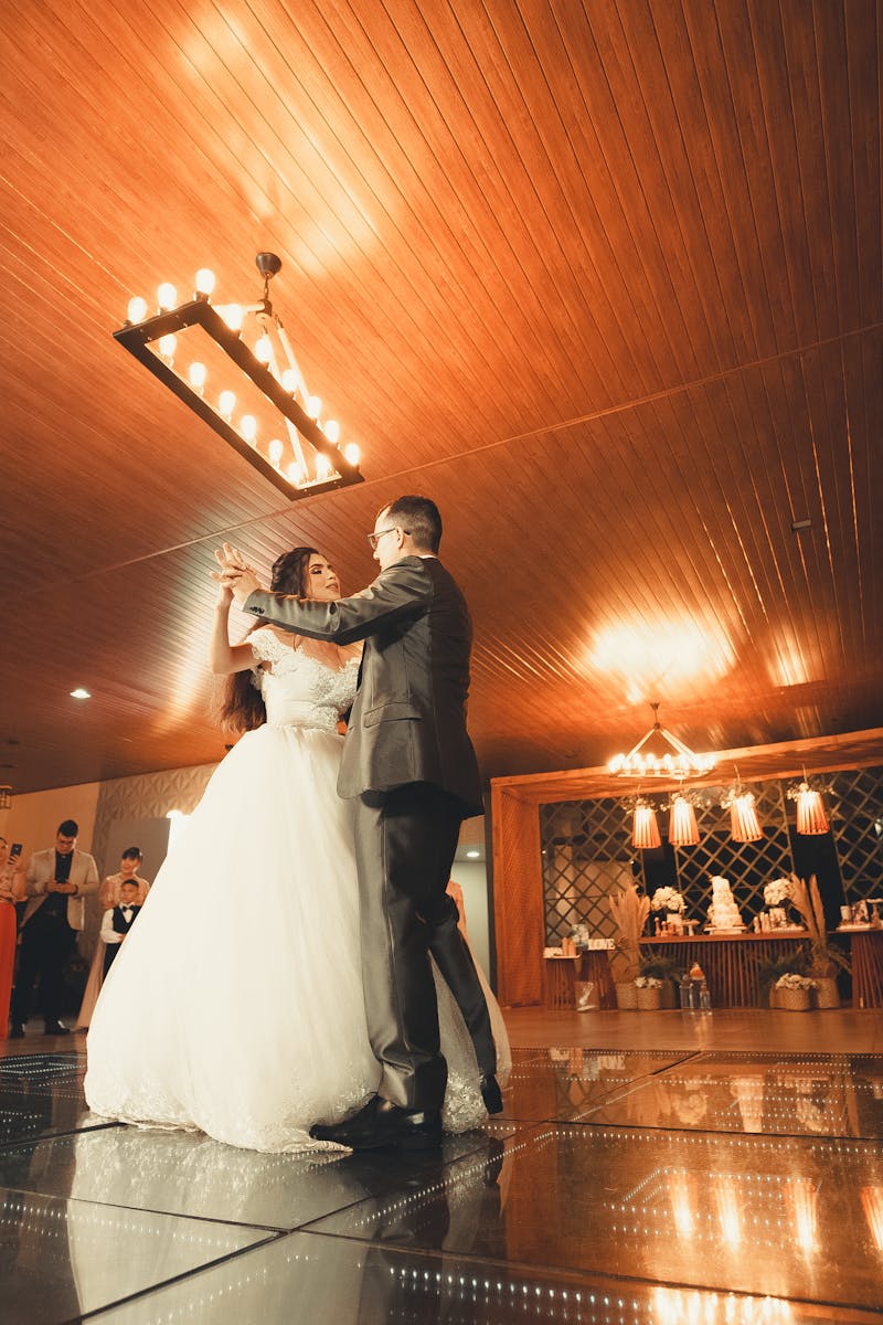Bride and groom share a magical first dance surrounded by guests at a wedding reception.
